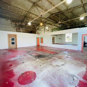 Large industrial room with red stained concrete floor and exposed metal trusses.