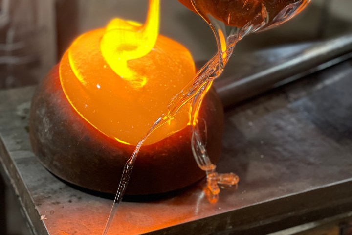 Molten glass being poured from a crucible on a metal surface.