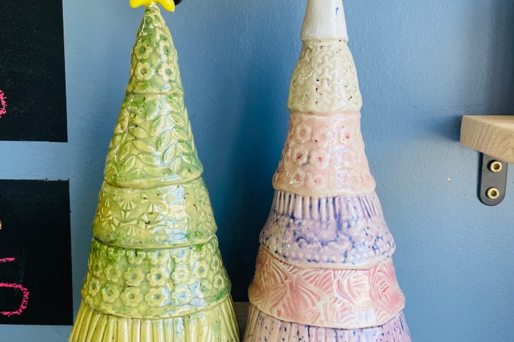 Two ceramic Christmas tree sculptures with star and heart toppers.